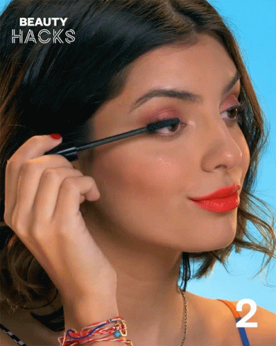 A Woman Is Applying Mascara And The Number 2 Is On The Bottom GIF