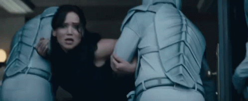 A Woman Is Being Held By A Man In A Blue Suit In A Room . GIF