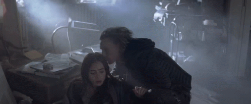A Woman Is Being Held By A Man In A Dark Room GIF