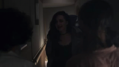 A Woman Is Being Held By Another Woman In A Dark Hallway GIF