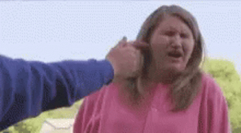 A Woman Is Being Punched In The Face By A Man In A Pink Shirt . GIF