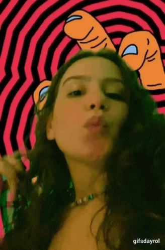 A Woman Is Blowing A Kiss In Front Of A Pink And Black Striped Background .. GIF