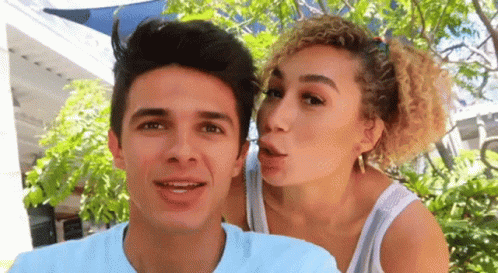 A Woman Is Blowing A Kiss On A Man 'S Face GIF