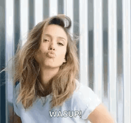 A Woman Is Blowing A Kiss While Wearing A White T-Shirt . GIF