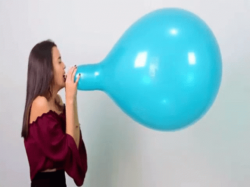 A Woman Is Blowing Up A Large Blue Balloon With Her Mouth . GIF