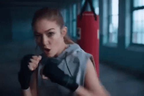 A Woman Is Boxing In A Gym With A Red Punching Bag . GIF