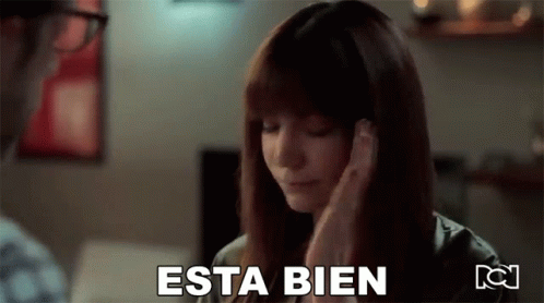 A Woman Is Covering Her Ears With Her Hands And The Word Esta Bien Is Written On The Screen . GIF