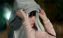 A Woman Is Covering Her Face With A Hooded Sweatshirt . GIF