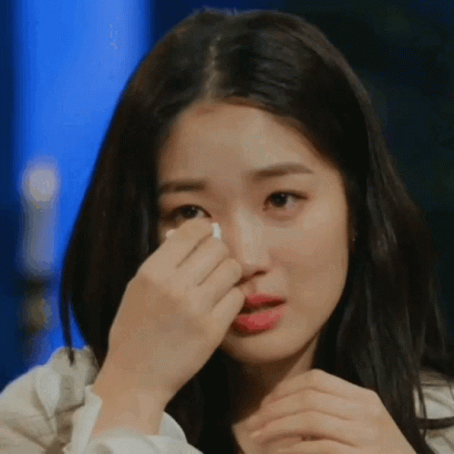A Woman Is Covering Her Face With Her Hand While Crying GIF