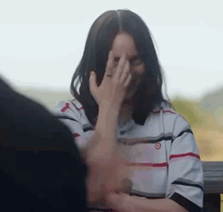 A Woman Is Covering Her Face With Her Hand While Sitting Next To A Man . GIF