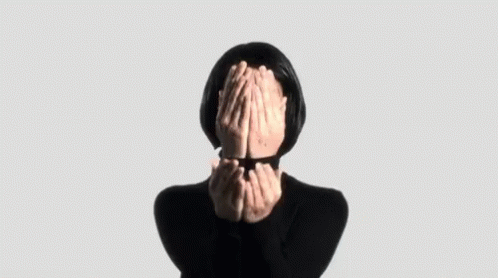 A Woman Is Covering Her Face With Her Hands In A Black Sweater . GIF