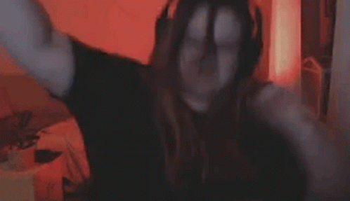 A Woman Is Covering Her Face With Her Hands While Sitting In Front Of A Computer Screen . GIF