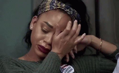A Woman Is Covering Her Face With Her Hands While Wearing A Headband . GIF