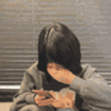 A Woman Is Covering Her Mouth While Looking At Her Phone . GIF