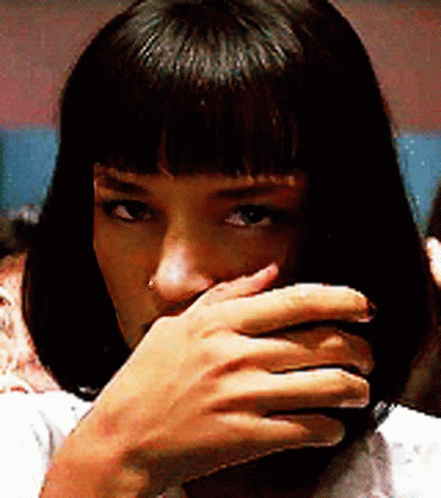 A Woman Is Covering Her Mouth With Her Hand And Looking At The Camera . GIF