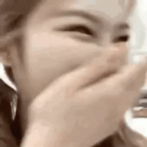 A Woman Is Covering Her Mouth With Her Hand While Laughing . GIF