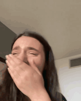 A Woman Is Covering Her Mouth With Her Hands While Crying . GIF