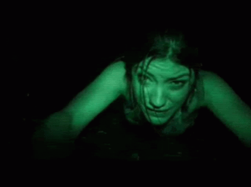 A Woman Is Crawling In The Dark With Green Light Coming Out Of Her Eyes . GIF