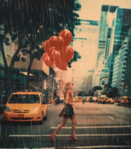 A Woman Is Crossing A Street In The Rain With Balloons In Her Hand GIF