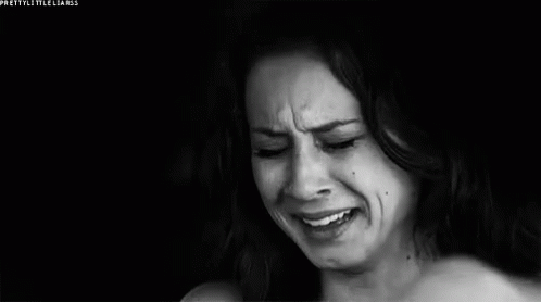 A Woman Is Crying In A Black And White Photo While Covering Her Face With Her Hand . GIF