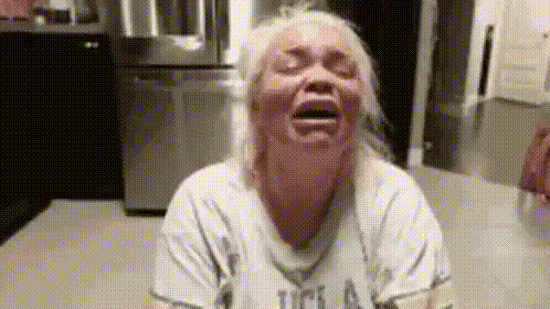 a woman is crying in a kitchen with her eyes closed and her mouth open .