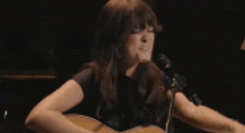 A Woman Is Crying In Front Of A Lamp In A Dark Room GIF