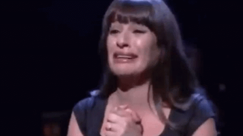 A Woman Is Crying On Stage While Holding Her Hands To Her Chest . GIF