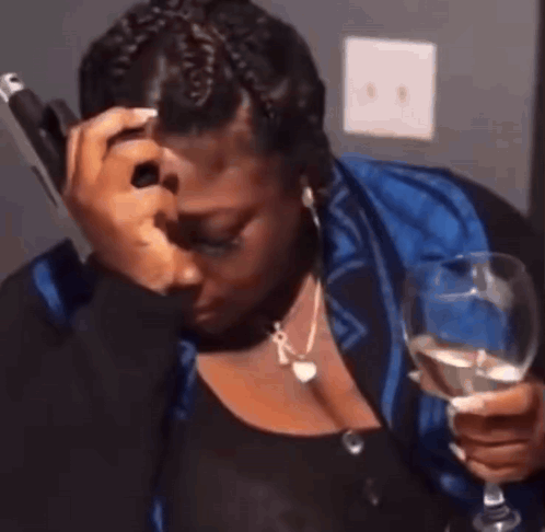 a woman is crying while holding a glass of wine and talking on a cell phone .