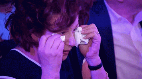 A Woman Is Crying While Holding A Tissue To Her Eye . GIF