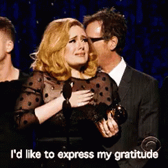 A Woman Is Crying While Holding A Trophy And A Man Is Kissing Her On The Cheek .. GIF