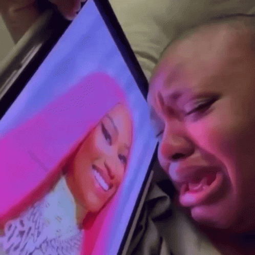A Woman Is Crying While Looking At A Picture Of Nicki Minaj On A Computer Screen . GIF