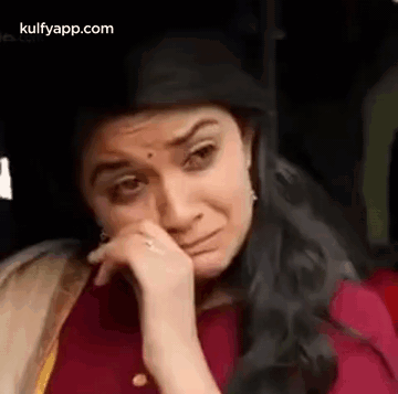 A Woman Is Crying While Sitting In A Car With Her Hand On Her Face . GIF