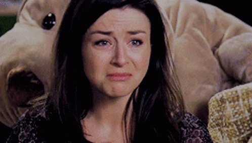 A Woman Is Crying While Sitting In Front Of A Stuffed Dog . GIF