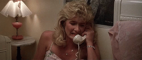 A Woman Is Crying While Talking On A Phone In A Bedroom . GIF