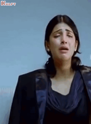 A Woman Is Crying While Wearing A Black Jacket And A Blue Top . GIF