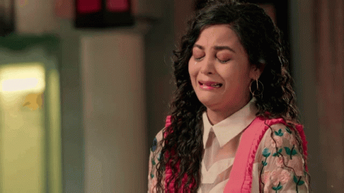 A Woman Is Crying With Her Eyes Closed And A Pink Shirt On GIF