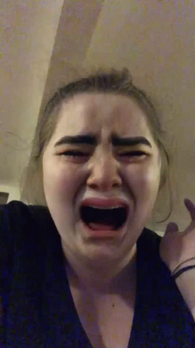 A Woman Is Crying With Her Mouth Open And Making A Funny Face . GIF
