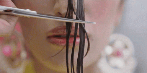 A Woman Is Cutting Her Hair With Scissors In Front Of Her Face GIF