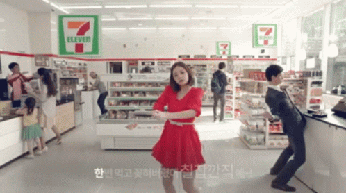A Woman Is Dancing In A 7 Eleven Store GIF