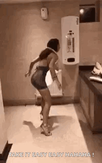 A Woman Is Dancing In A Bathroom With The Words `` Take It Easy Easy Hahaha '' Written On The Bottom . GIF