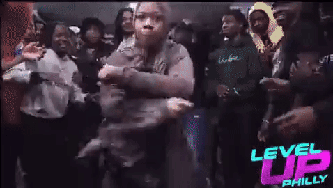 A Woman Is Dancing In A Crowd Of People At A Party . GIF
