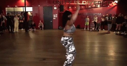 A Woman Is Dancing In A Dance Studio In Front Of A Crowd . GIF