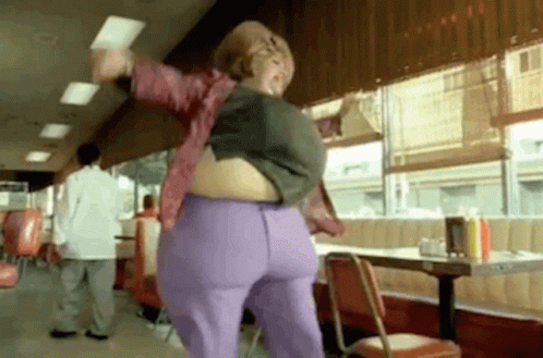 A Woman Is Dancing In A Diner With A Very Large Belly . GIF