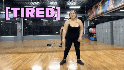 A Woman Is Dancing In A Gym With The Words Tired Above Her GIF