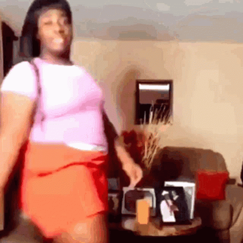 A Woman Is Dancing In A Living Room In Front Of A Couch And A Table . GIF