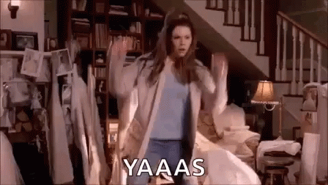 A Woman Is Dancing In A Living Room In Front Of A Staircase In A House . GIF
