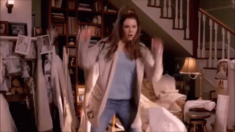 A Woman Is Dancing In A Living Room In Front Of Stairs . GIF