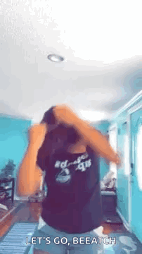 A Woman Is Dancing In A Living Room While Wearing A Black Shirt . GIF