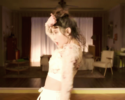 A Woman Is Dancing In A Room With A Ceiling Fan GIF