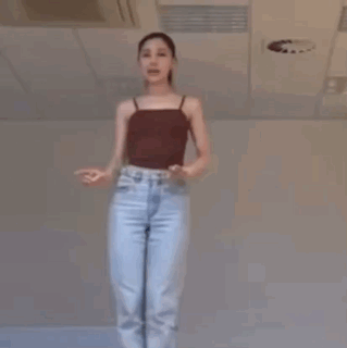 A Woman Is Dancing In A Room With A Ceiling Fan . GIF